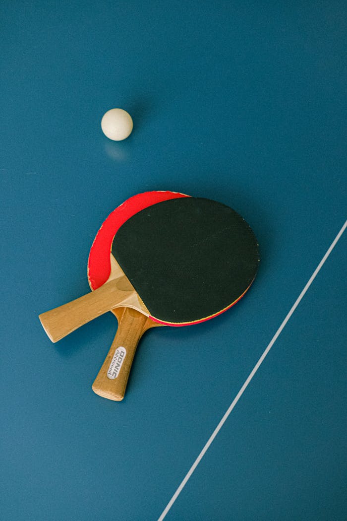 Flat lay of ping pong paddles and ball on a table tennis surface.