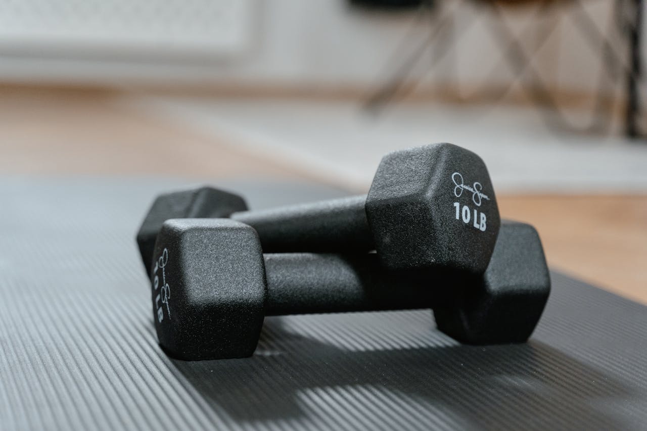 A close-up shot of 10-pound dumbbells placed on a ribbed exercise mat, ideal for fitness themes.